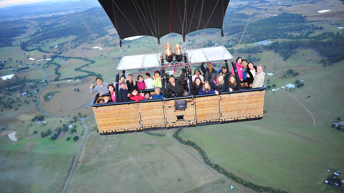 Hot air balloon drifting over hinterland farmland