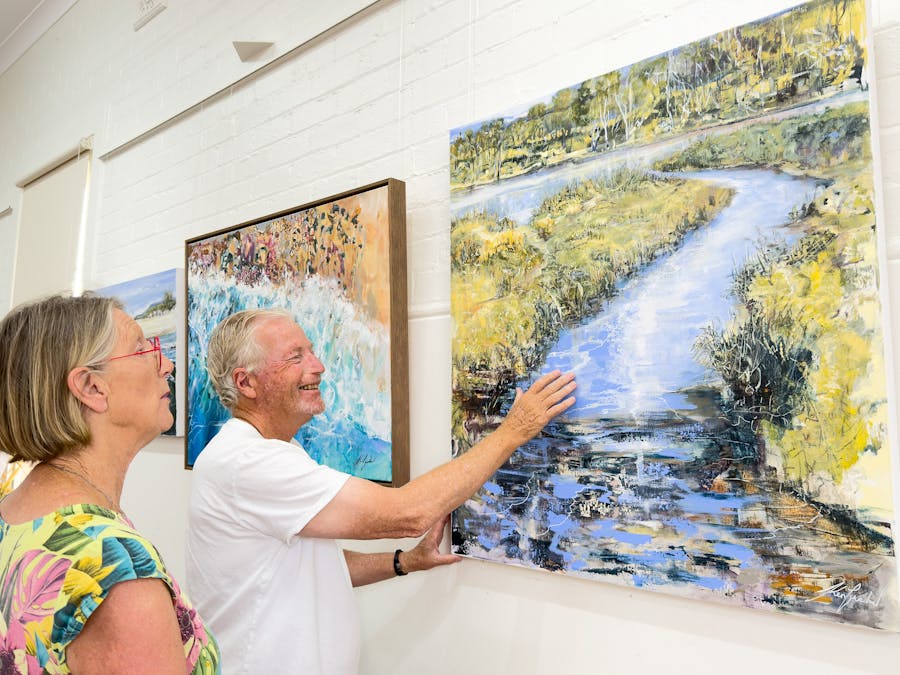 Two people looking at a painting in a gallery