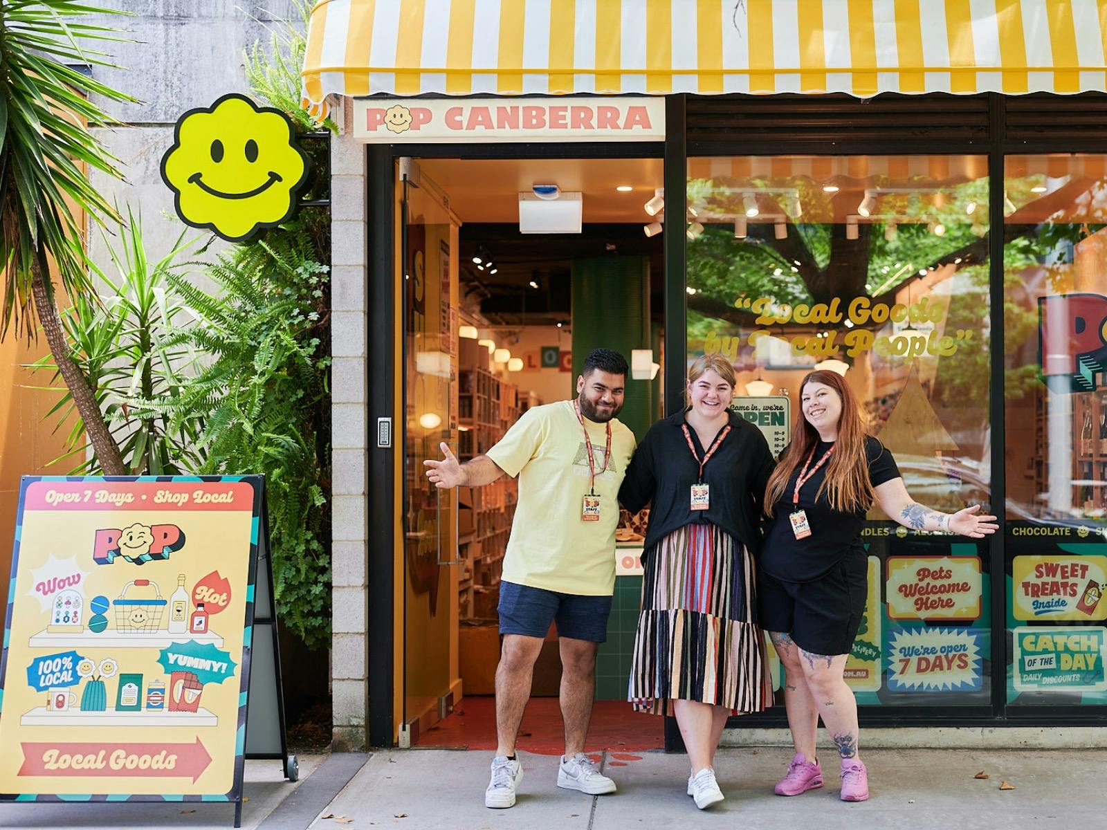 A vibrant storefront of POP Canberra with three smiling staff members outside, promoting local goods