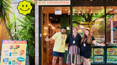 A vibrant storefront of POP Canberra with three smiling staff members outside, promoting local goods