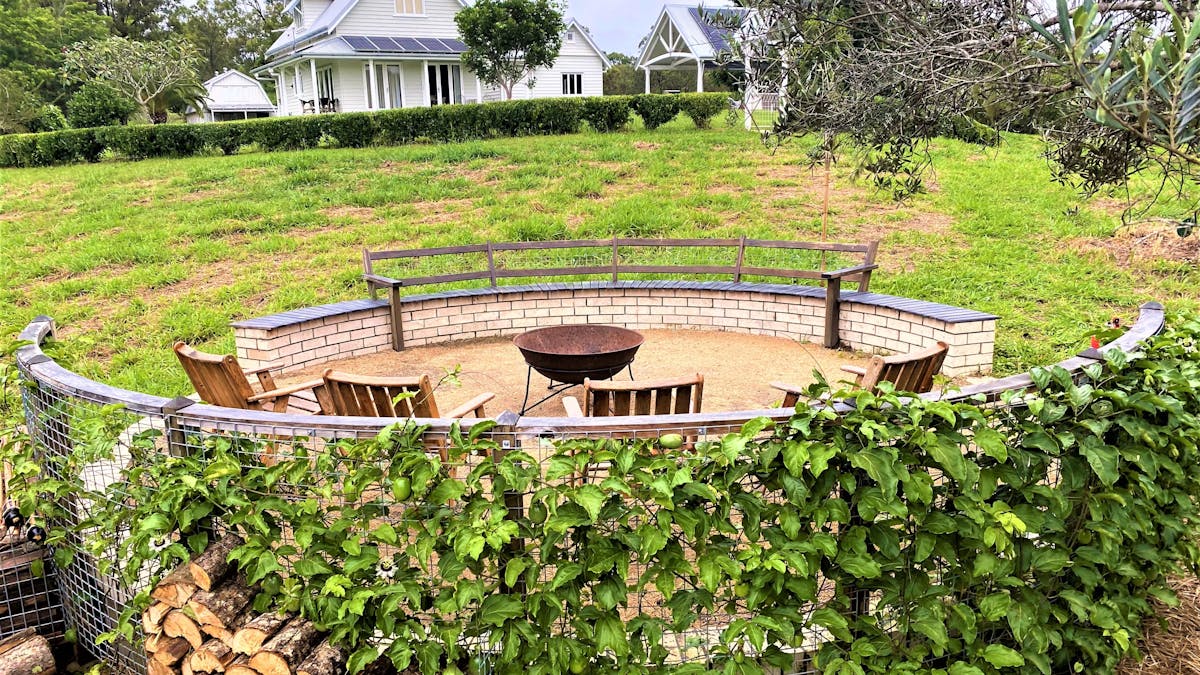 rural outdoor firepit with bench and chairs and stacked logs
