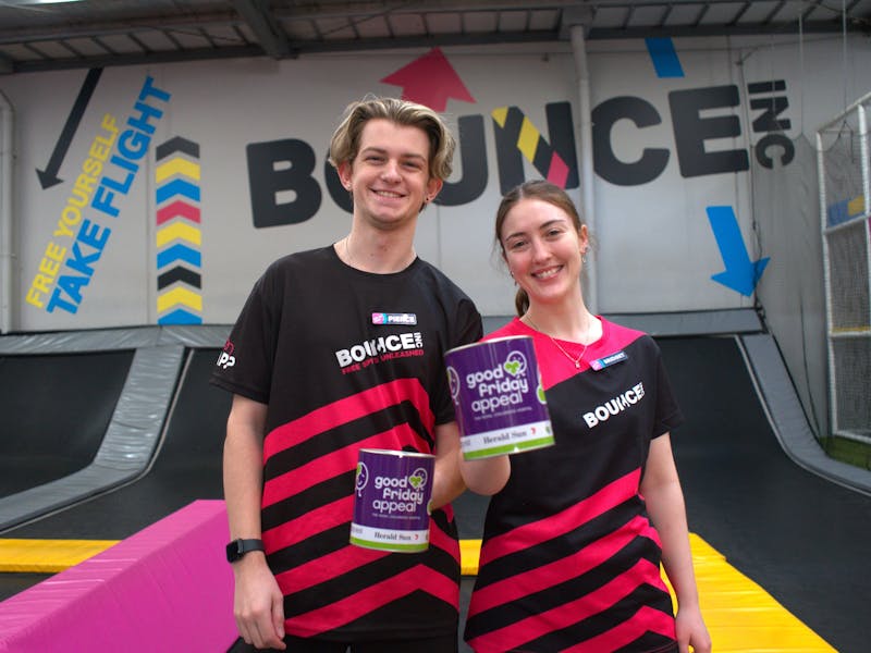 Two BOUNCE employees pictured smiling and holding a Good Friday Appeal fundraising tin