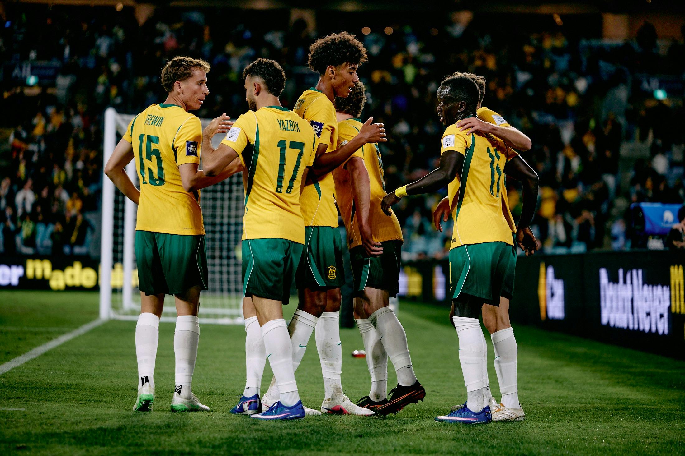 Soccer players in yellow kits celebrate a goal on a stadium pitch