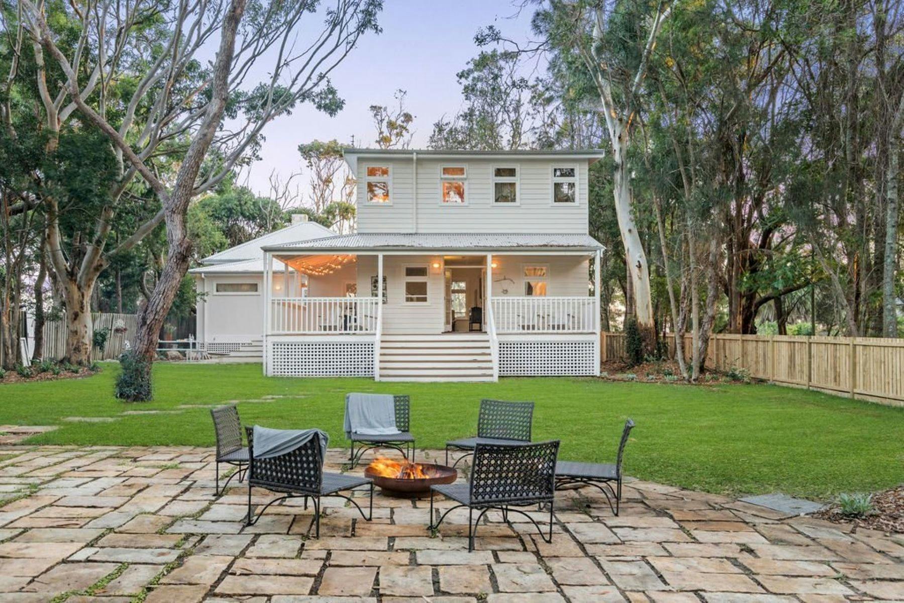 Image of the back view of property. Firepit is set up with fire going and chairs for guests to relax