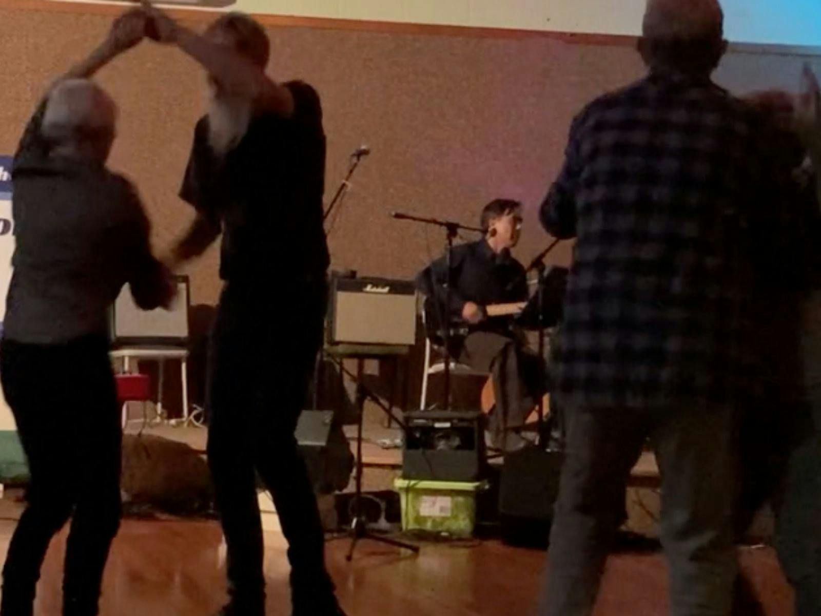 two couples dancing with guitarist on stage in background