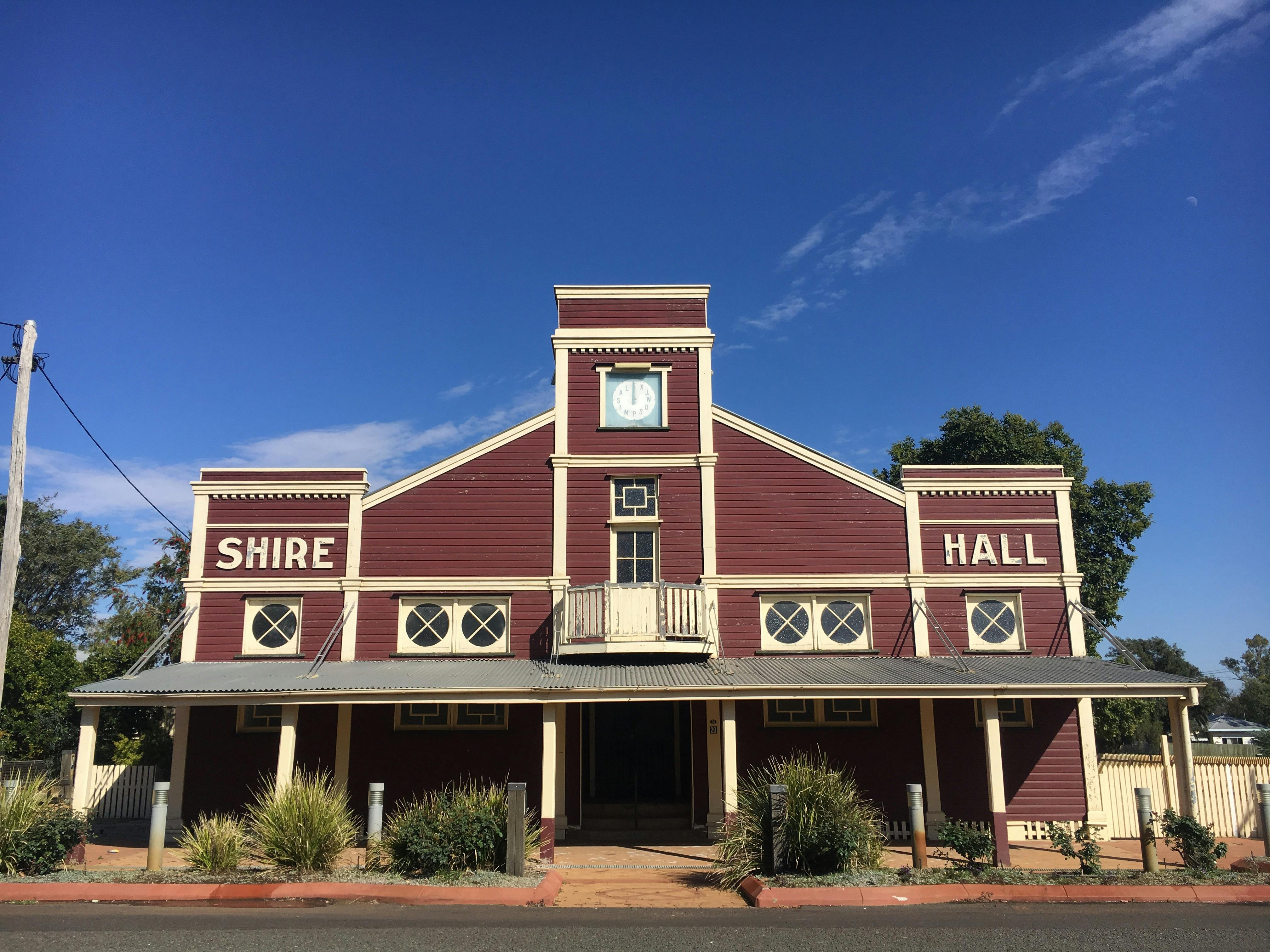 Front facade of the Surat Shire Hall, a dark red art-deco building with white trim