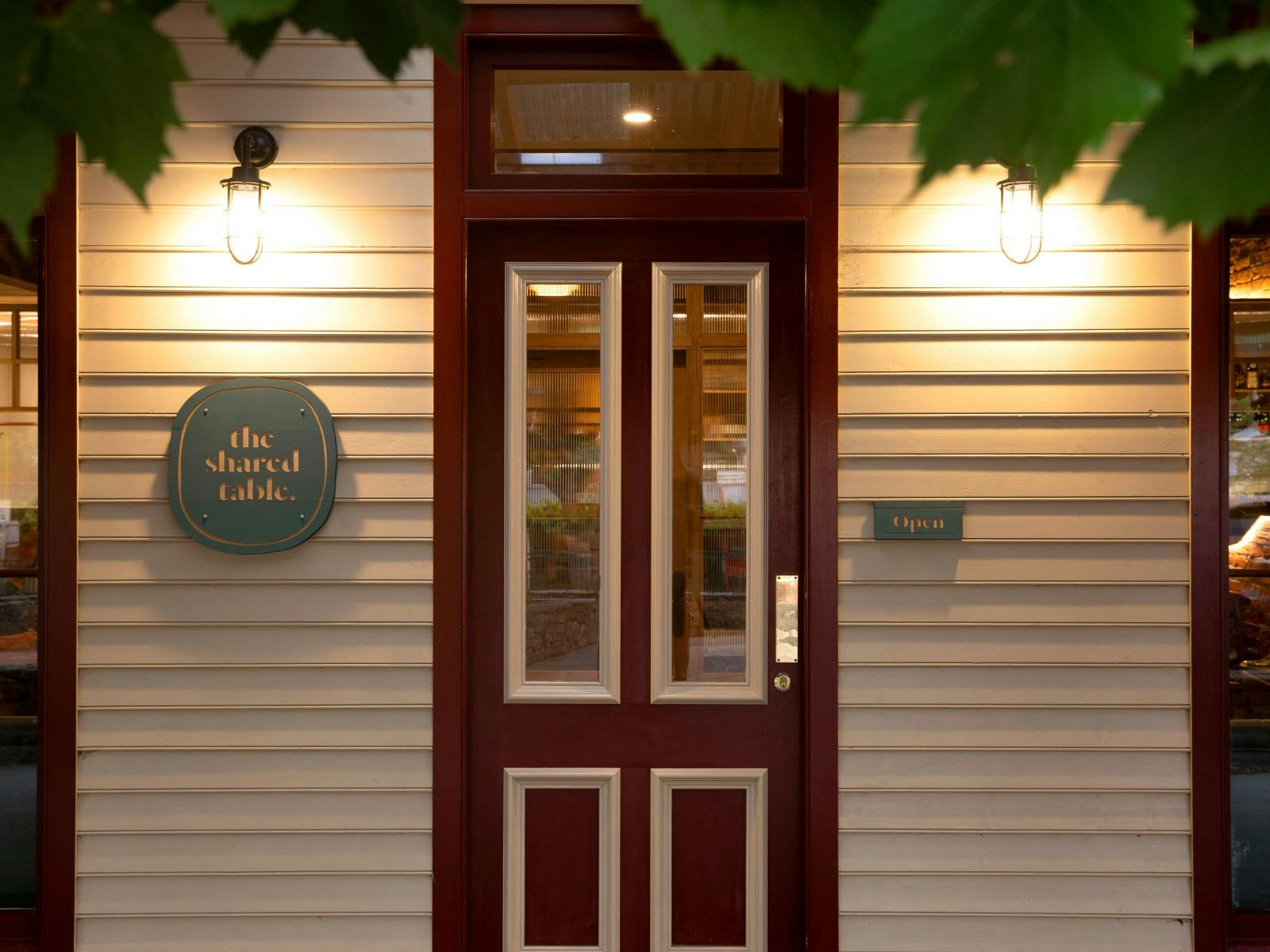 Front door of The Shared Table looking through grape vine leaves