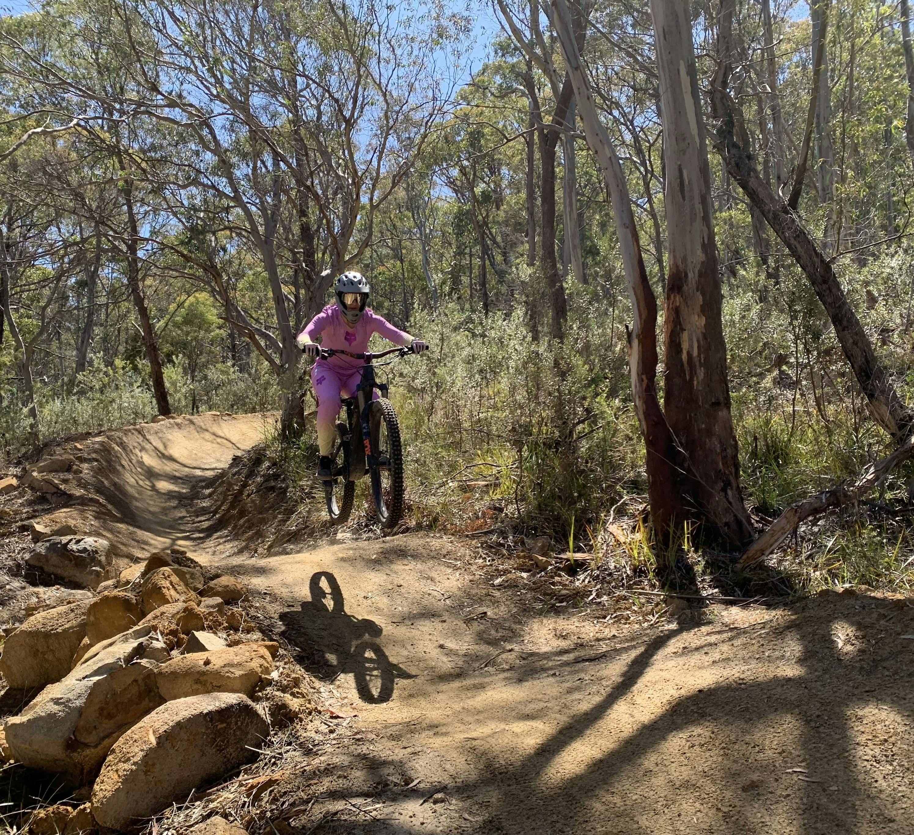 A young rider is riding the trail in a bushland setting.