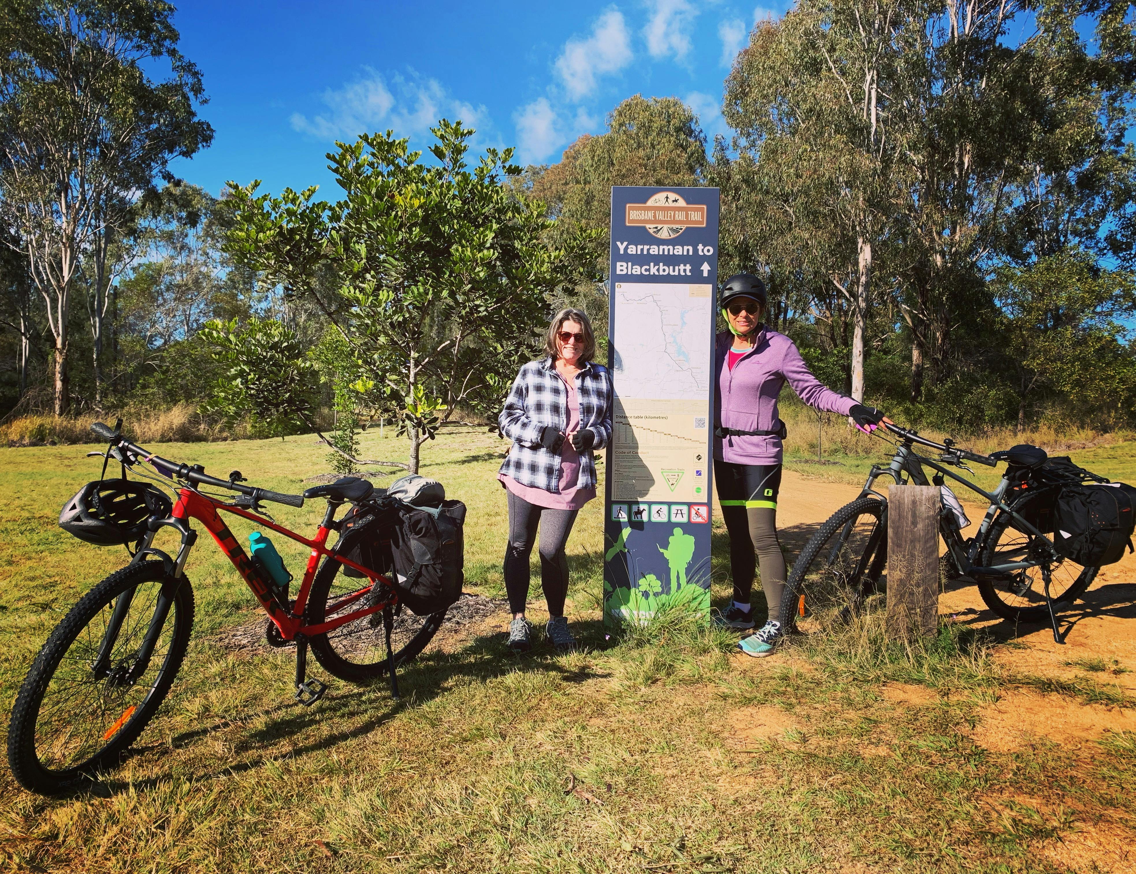 riders with bikes standing beside a sign