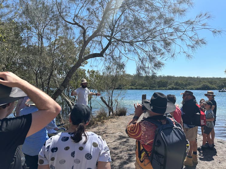Group listening to traditional dreamtime story on the riverbank