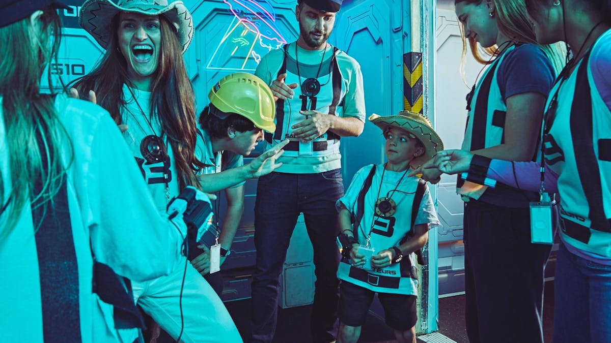 Adults and children in Saboteurs gear react with shock and laughter during gameplay.