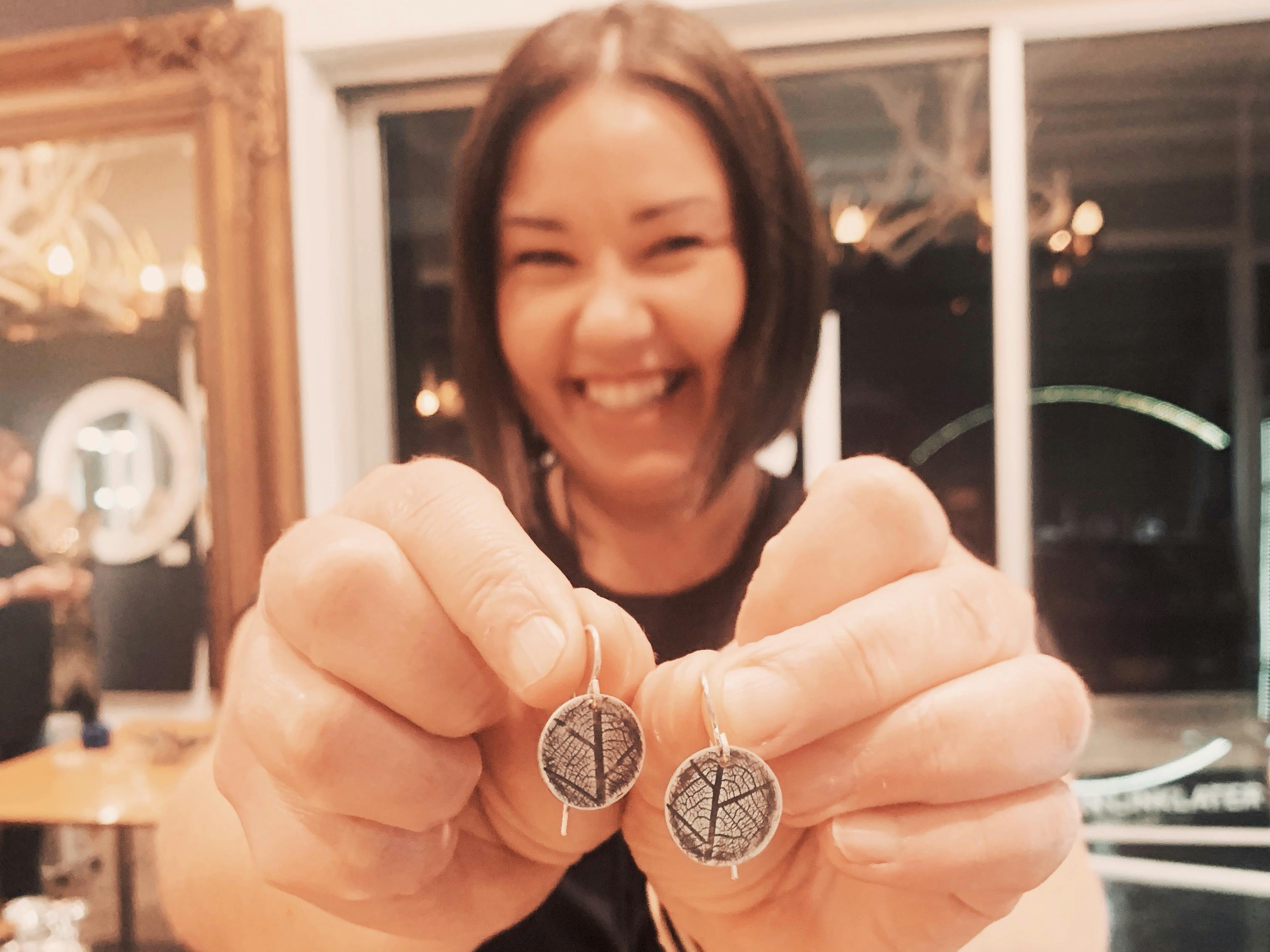 Workshop attendee holds up the earrings she made