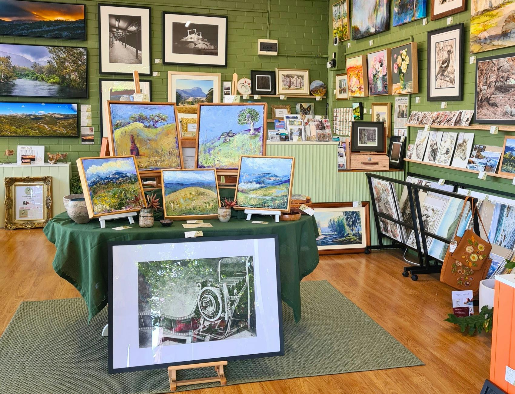 Artworks displayed on a central table and artworks hung on the walls
