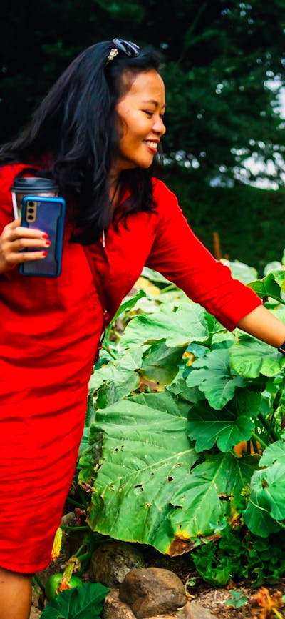 Woman reaching out towards large pumpkin in Lanyon Homestead gardens