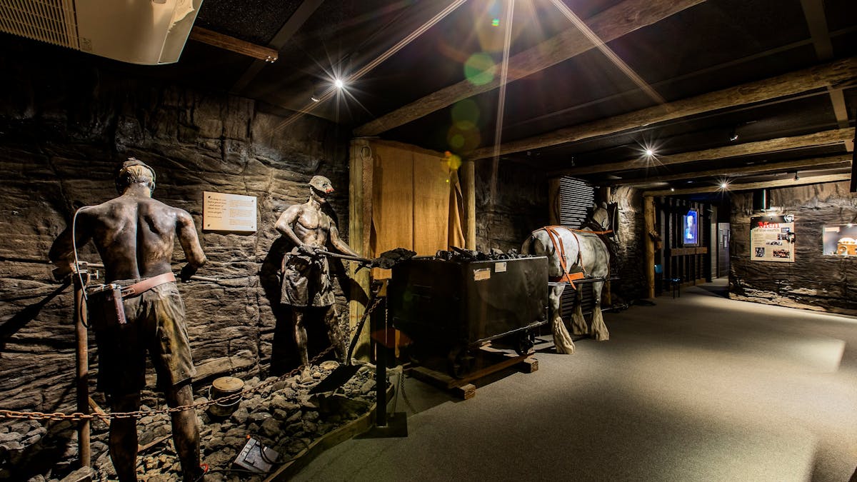 Iron sculptures of two miners loading coal into horse drawn carriage