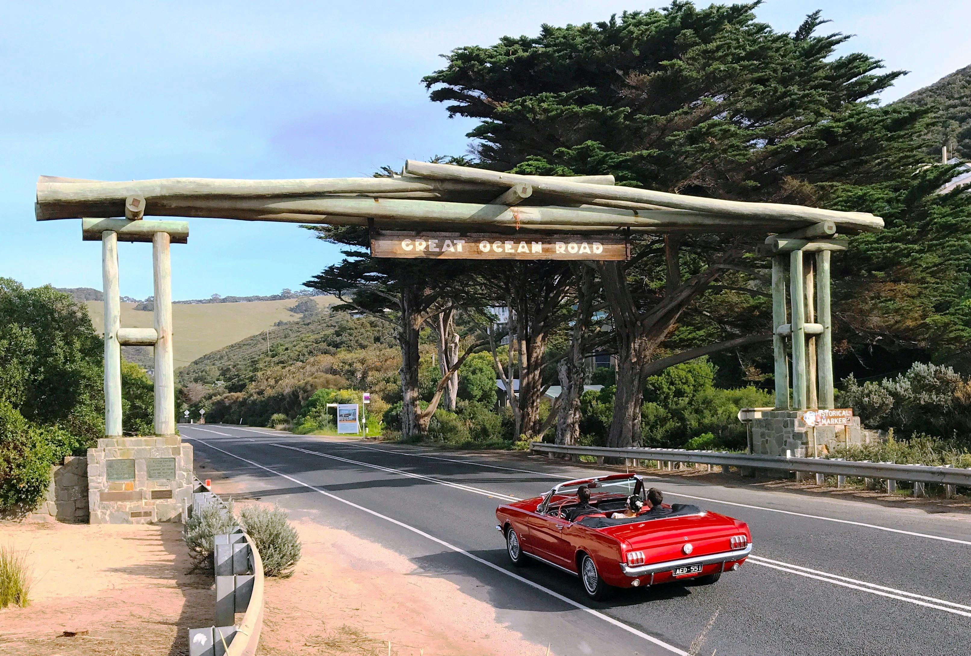 Vintage Mustang passing under the Great Ocean Road Arch on tour to Lorne with photo stops along.