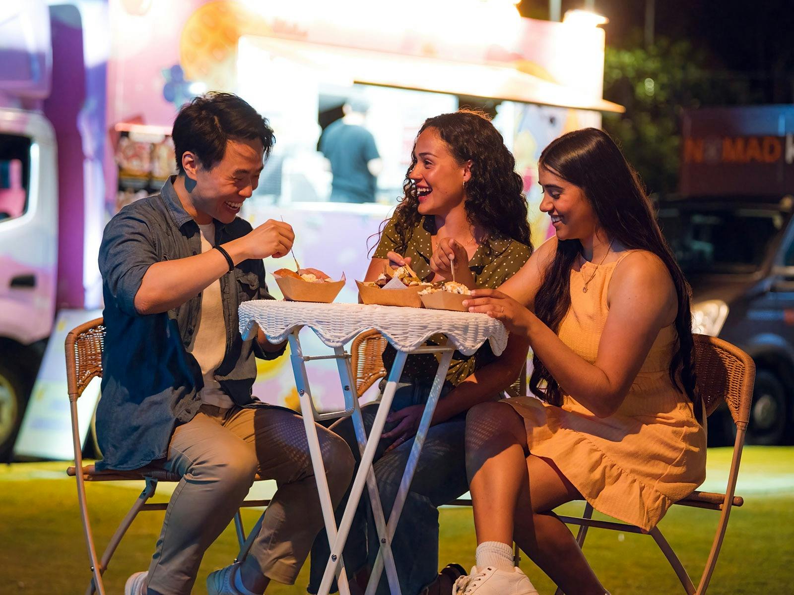 Three people seated at a table outside eating