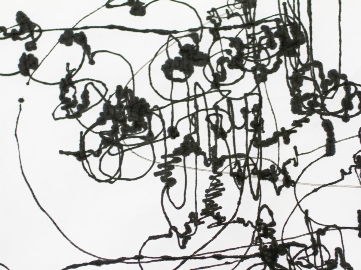 Dried black ink is dribbled across a white background in blots, big loops, lines and squiggles