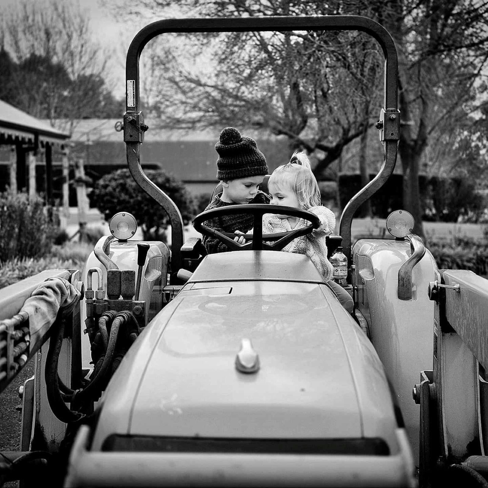 two children sitting behing the steering wheel of a tractor at Flowerdale Estate