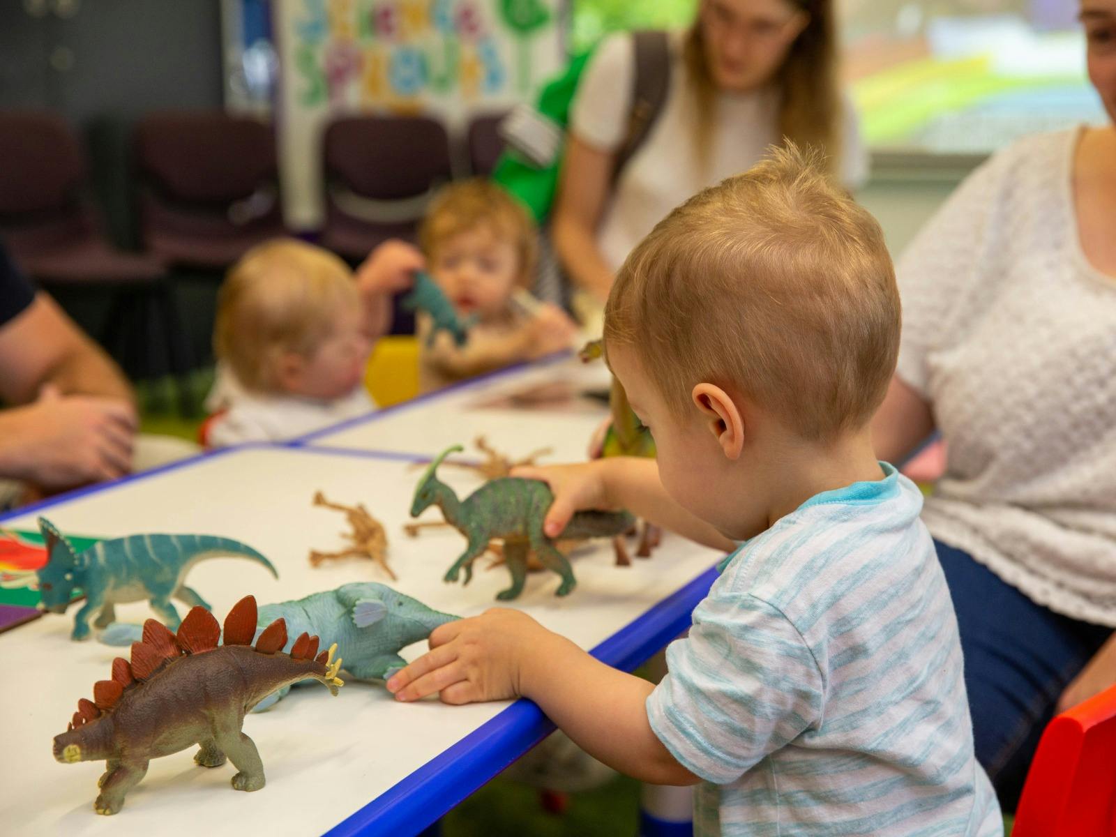 A young boy plays with toy dinosaurs at Science Time