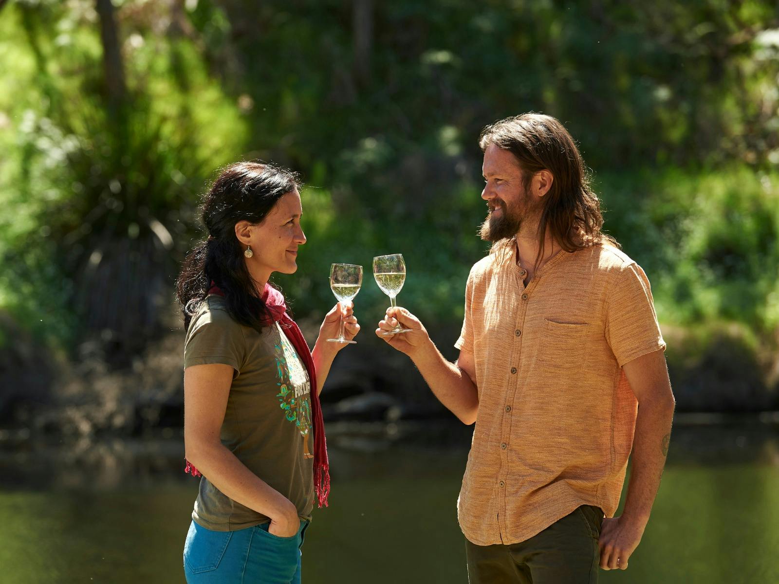 a couple raising glasses of wine  in outdoors setting