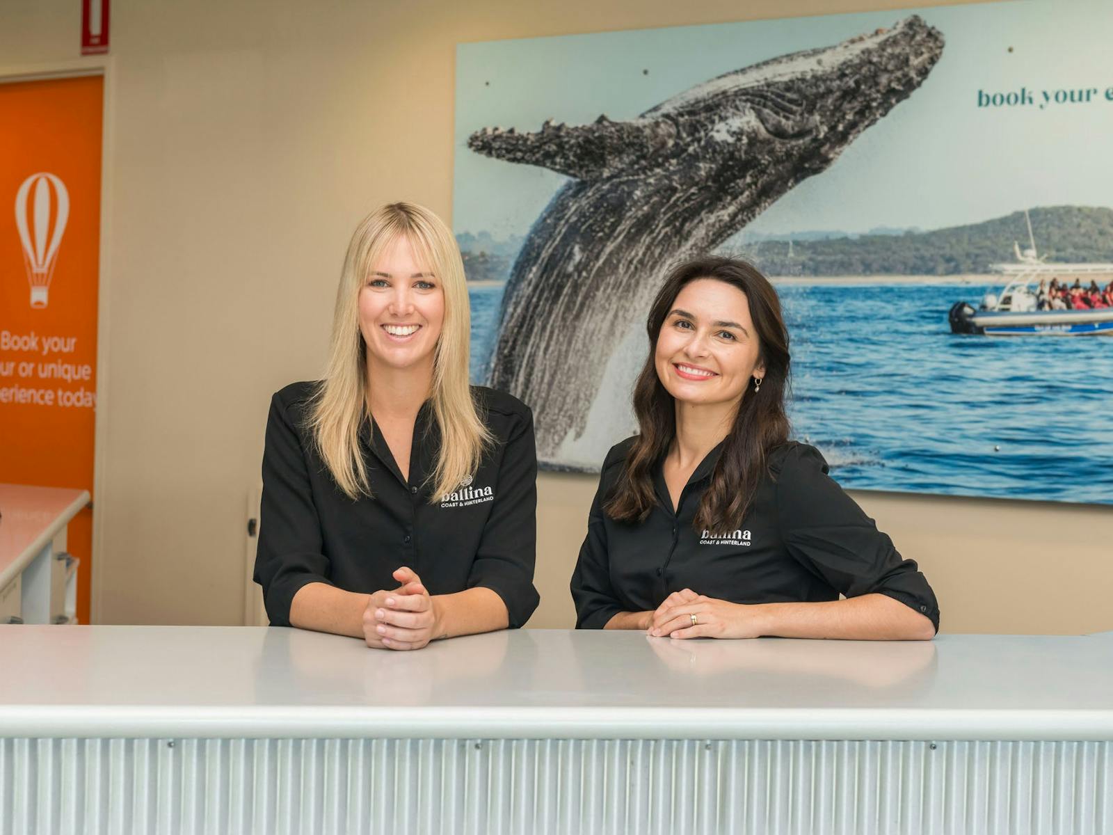 Two staff members standing behind the counter of the Ballina Visitor Information Centre