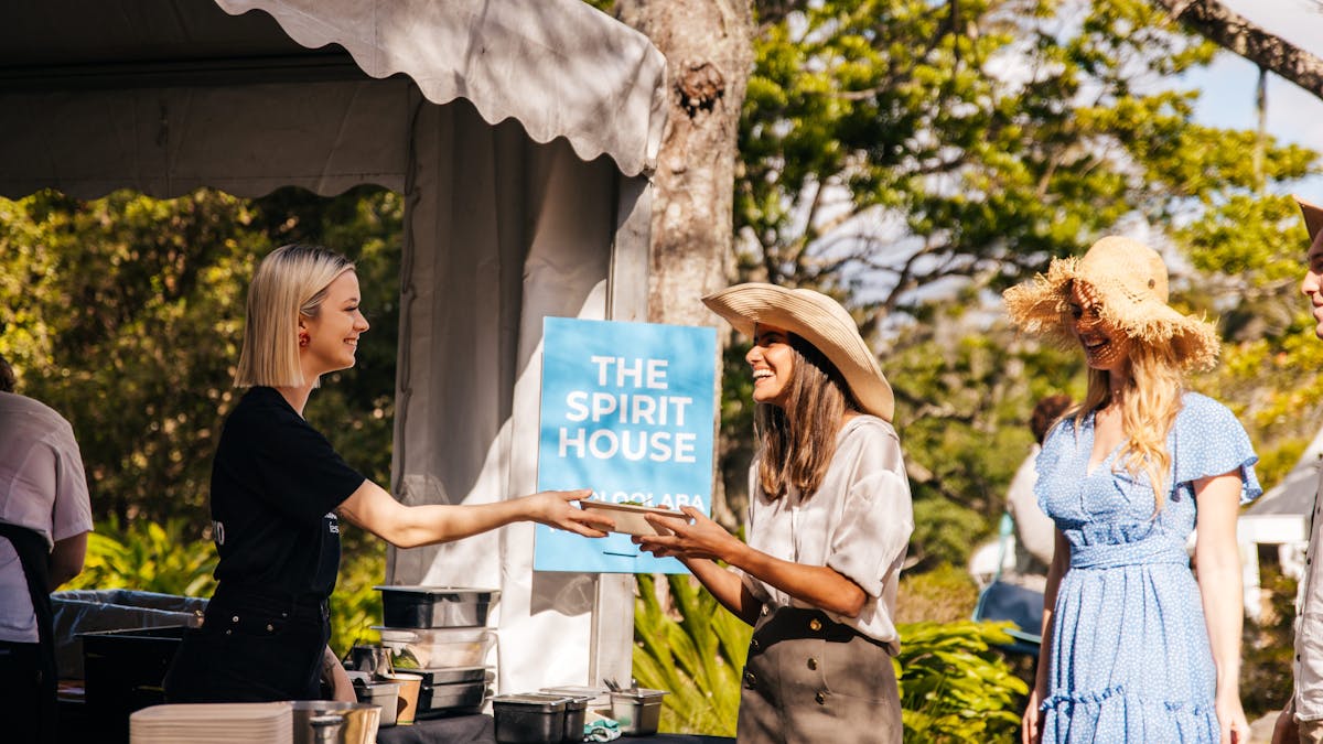 Two women at the festival getting food from a Spirit House food stall