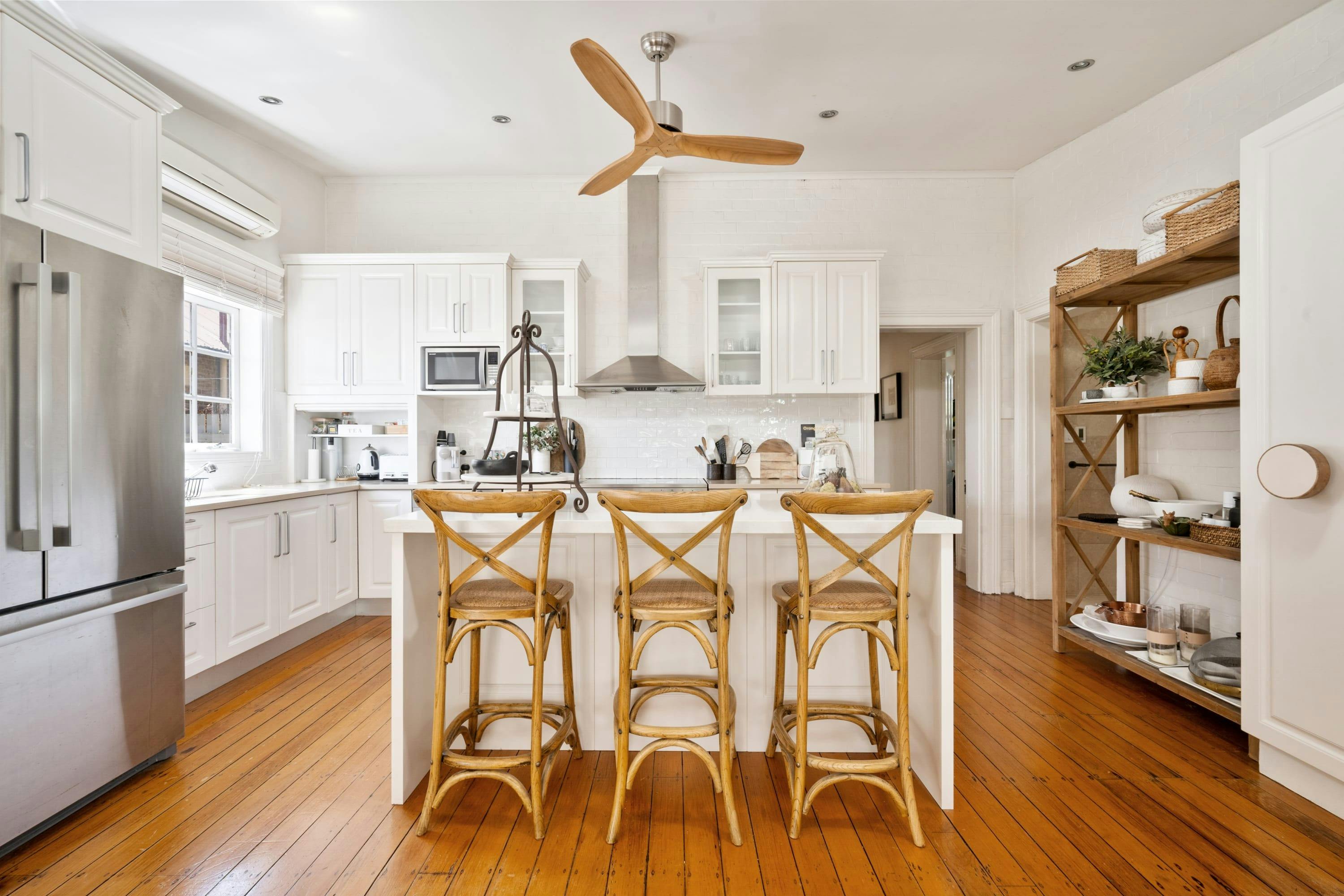 Large modern white kitchen with decor and rattan stools. Ultimate hosting space for guests