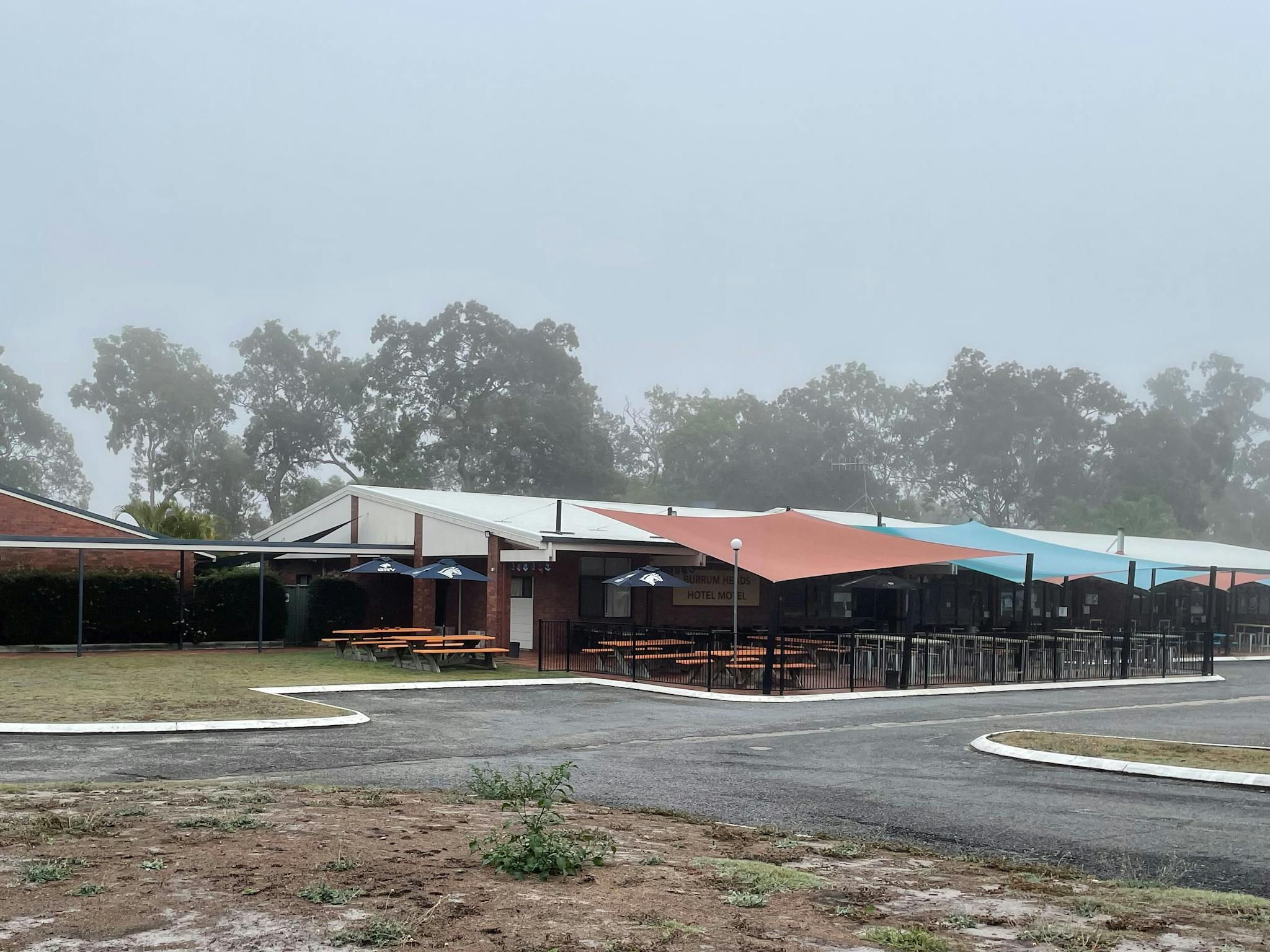 photo showing Burrum Heads Hotel Motel facade with outdoor seating area on a foggy morning photo showing Burrum Heads Hotel Motel facade with outdoor seating area on a foggy morning