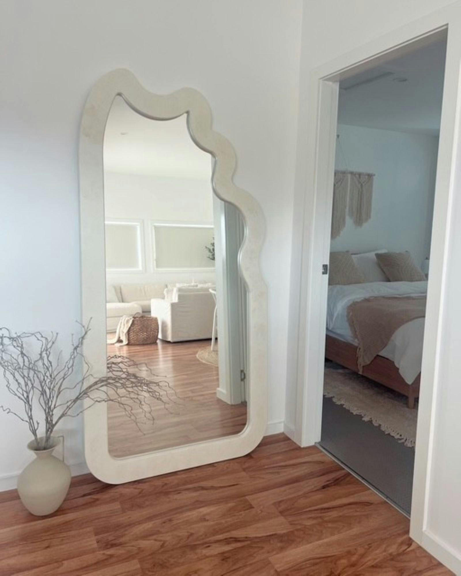 large mirror reflecting the living area. Doorway into bedroom