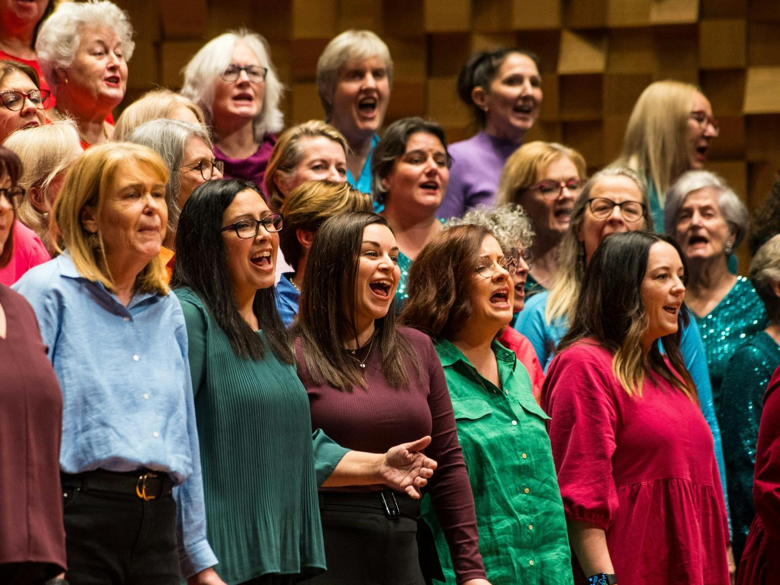 Choir of women singing passionately during an a cappella workshop.