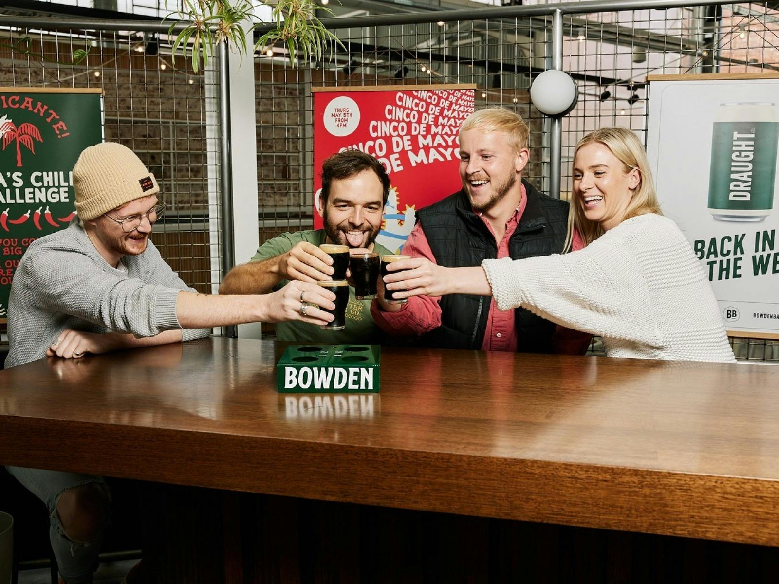 4 people stand over table and cheers