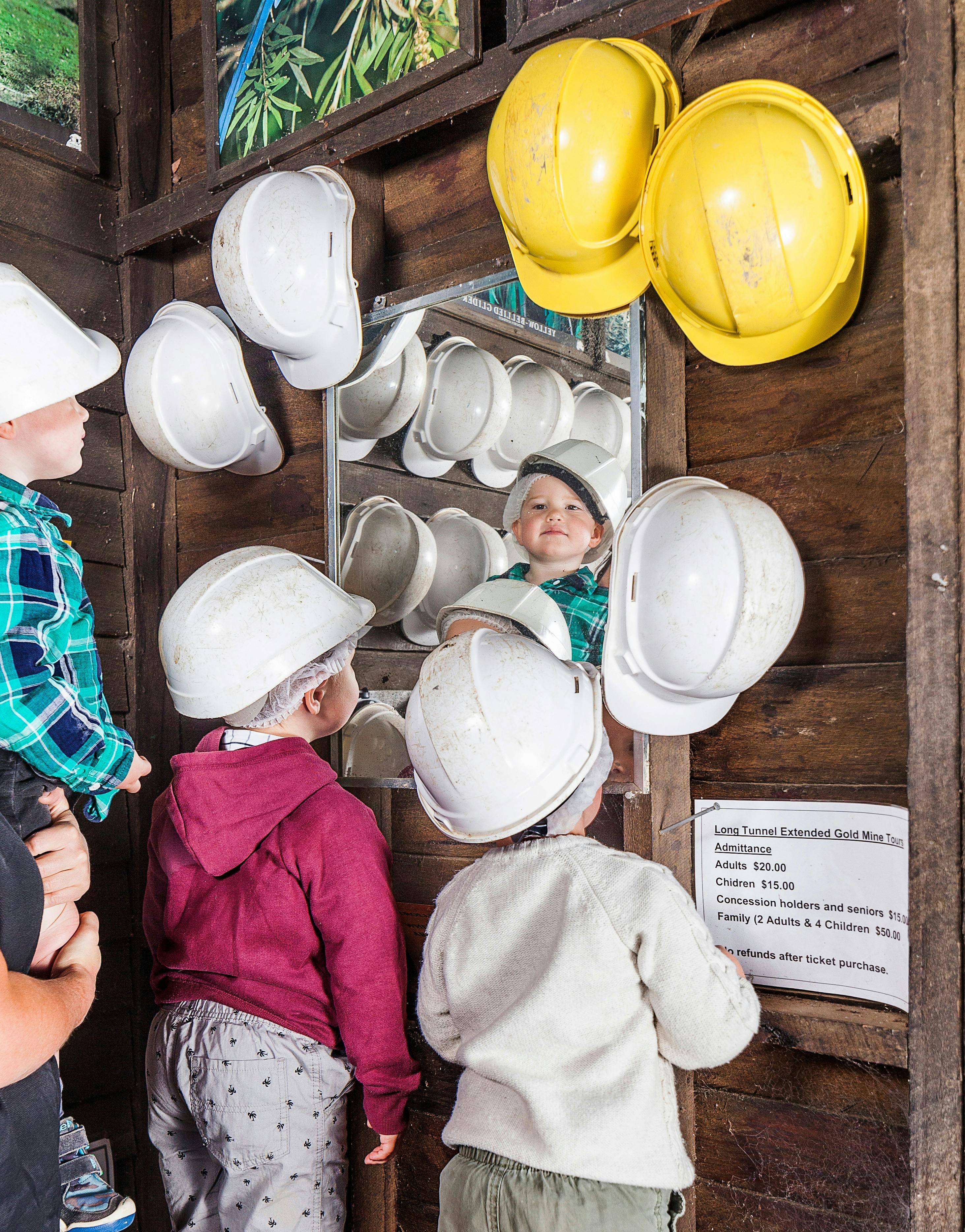 Young children choosing their helmets before going underground on a tour.
