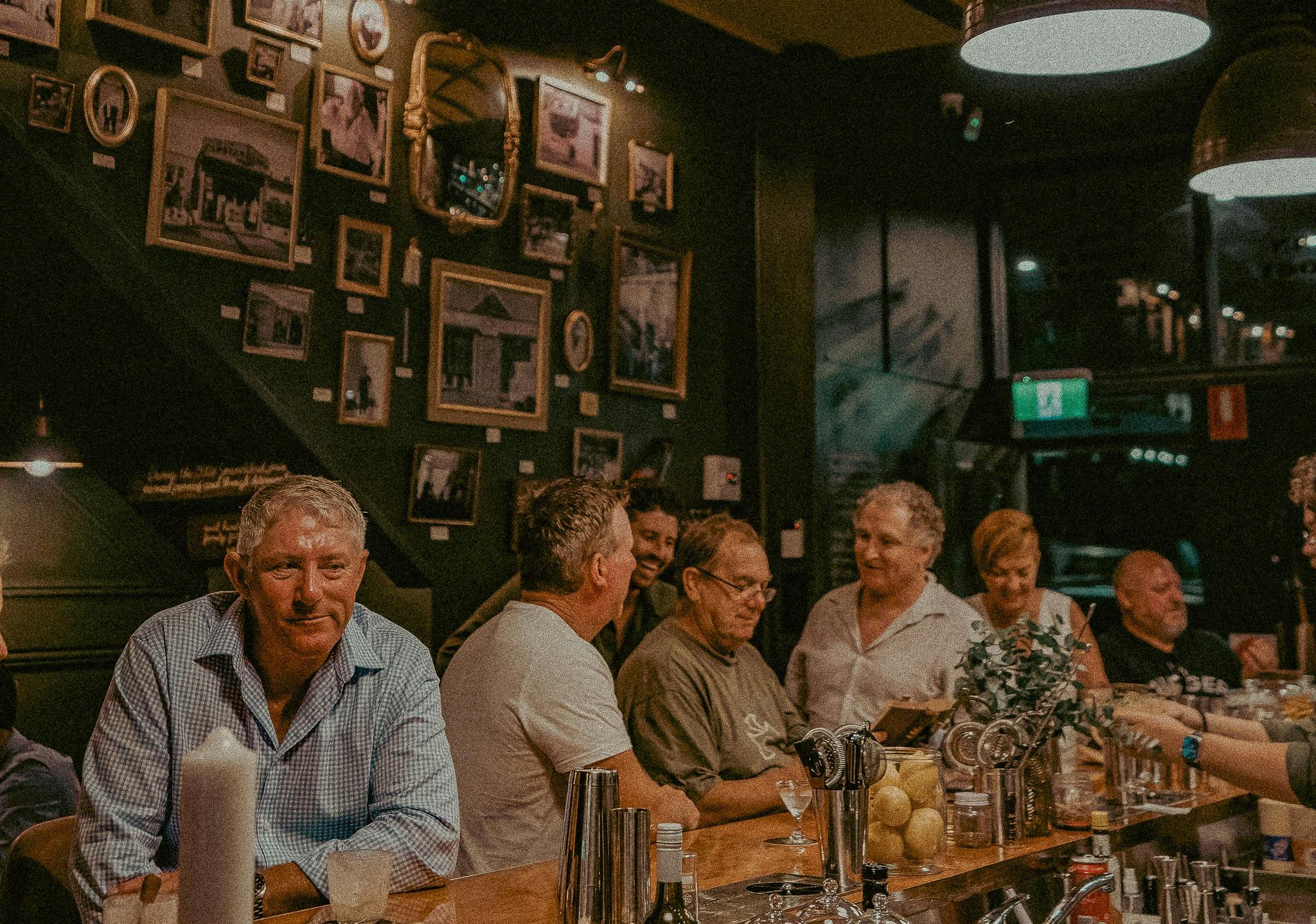 Customers sitting at the bar of Granddad's Bar enjoying a chat and a cocktail.