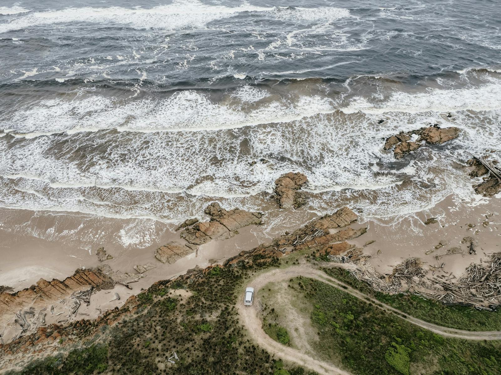 Aerial view of vehicle traversing the winding off-road track along the North West Coast.
