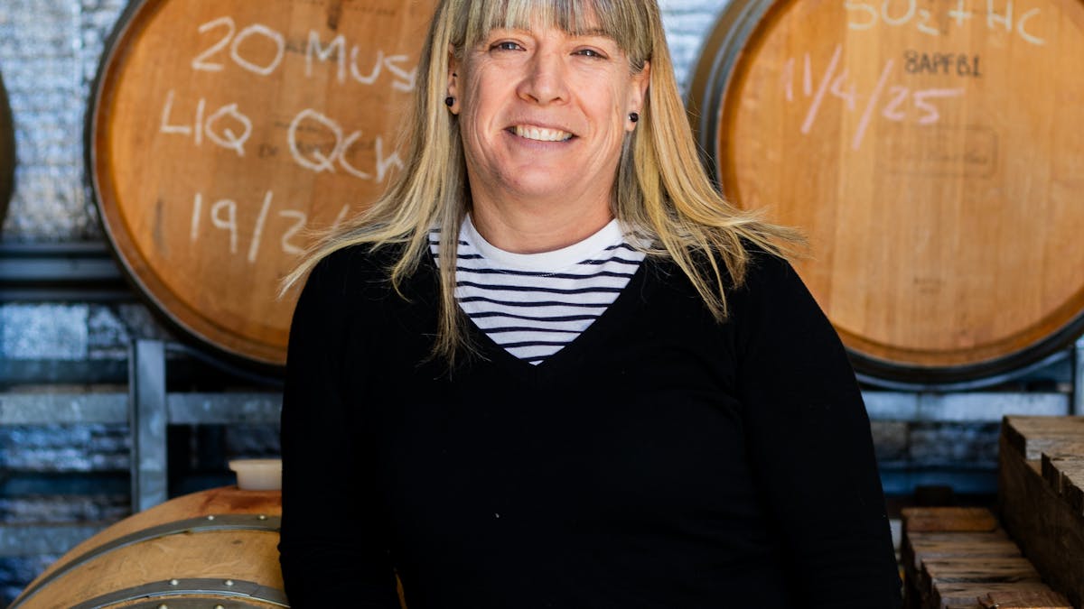 Winemaker leaning on wine barrels