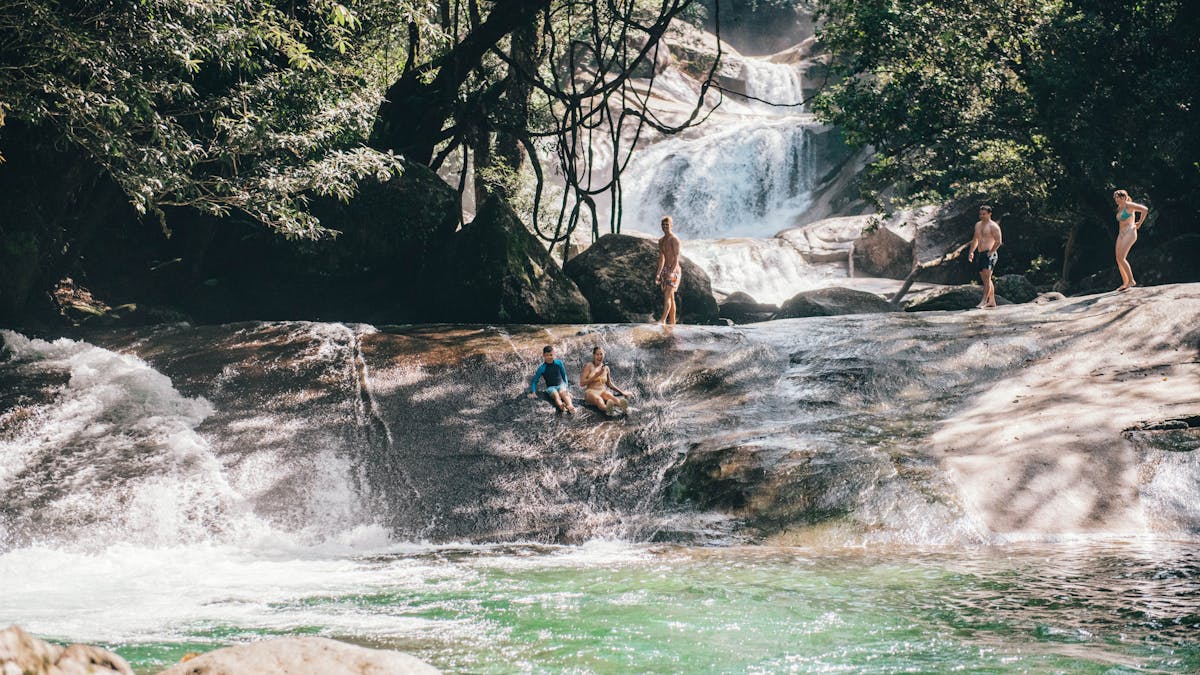 Two guest slide down the natural rock water slide at Josephine Falls in Tropical North Queensland
