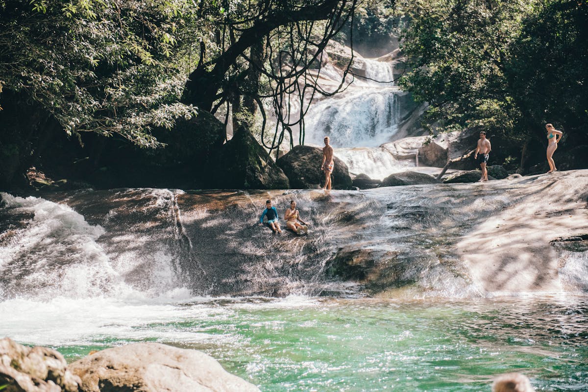 Two guest slide down the natural rock water slide at Josephine Falls in Tropical North Queensland