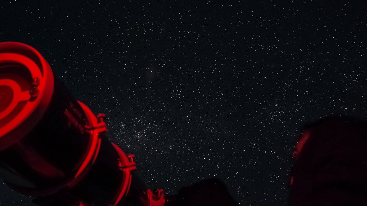 Stargazers peering through a telescope into the night sky.