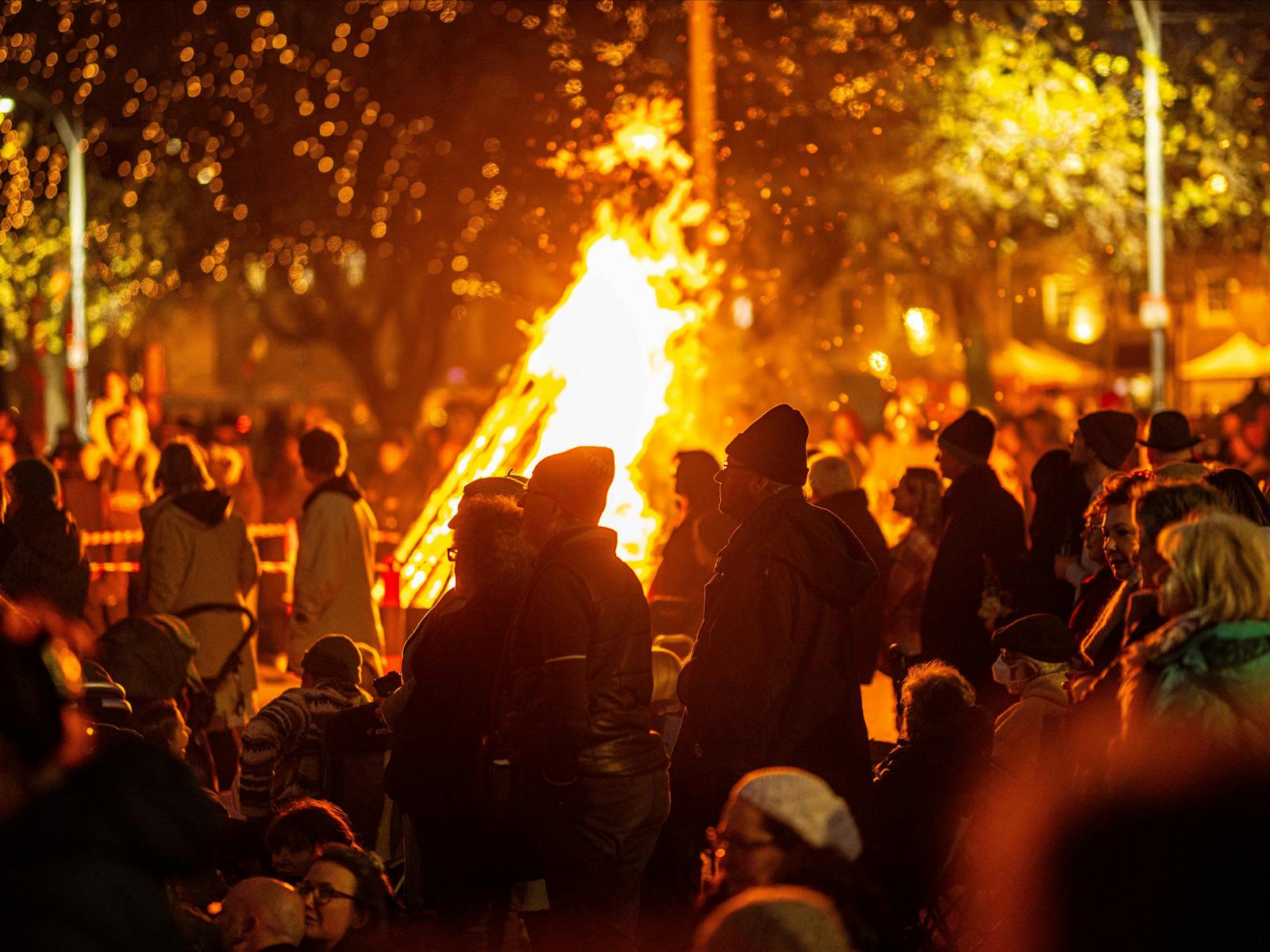 A colour photograph of people standing around a bonfire singing together at Festival of Voices