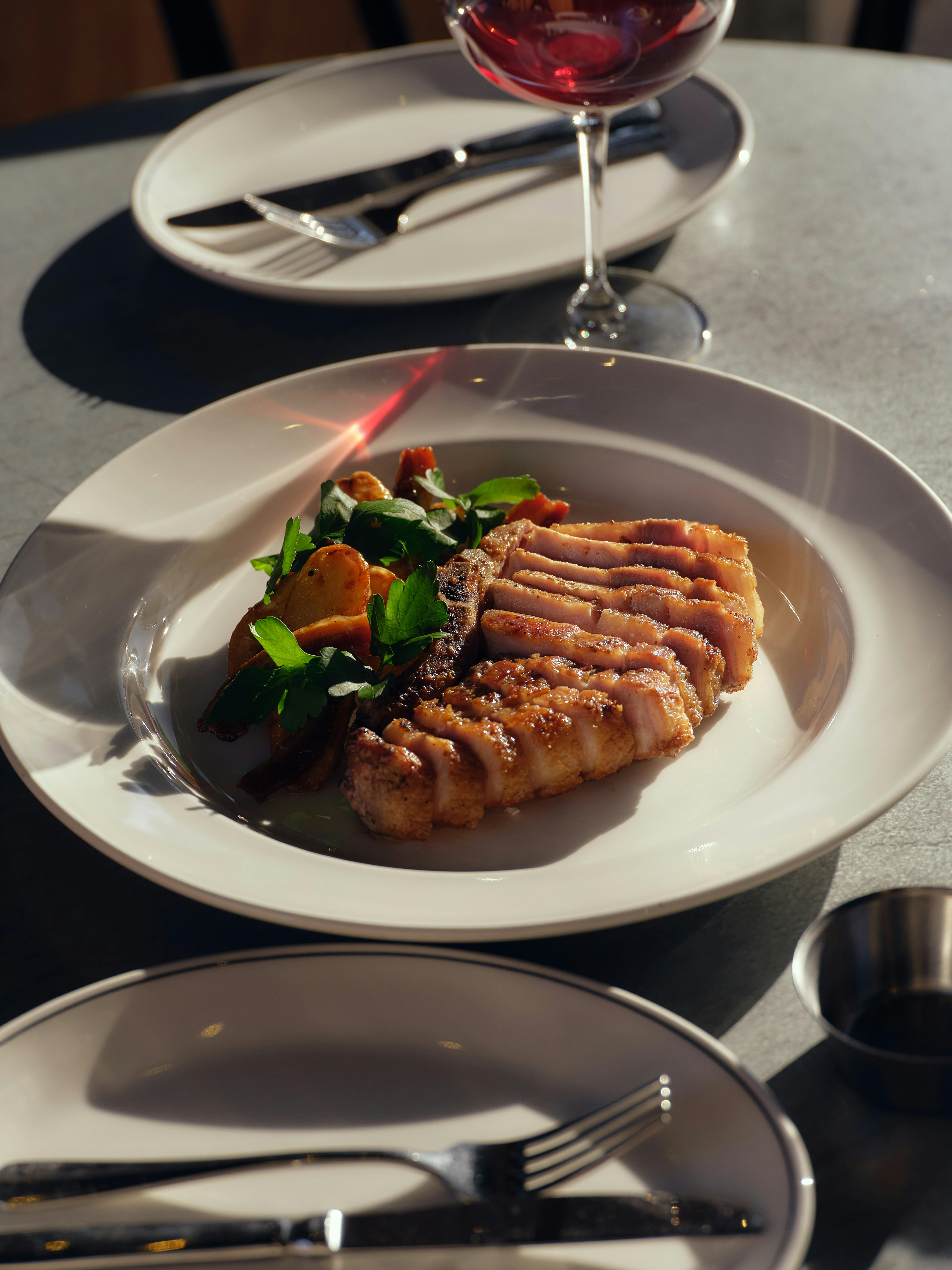 A plate of sliced pork chop, potatoes, salad