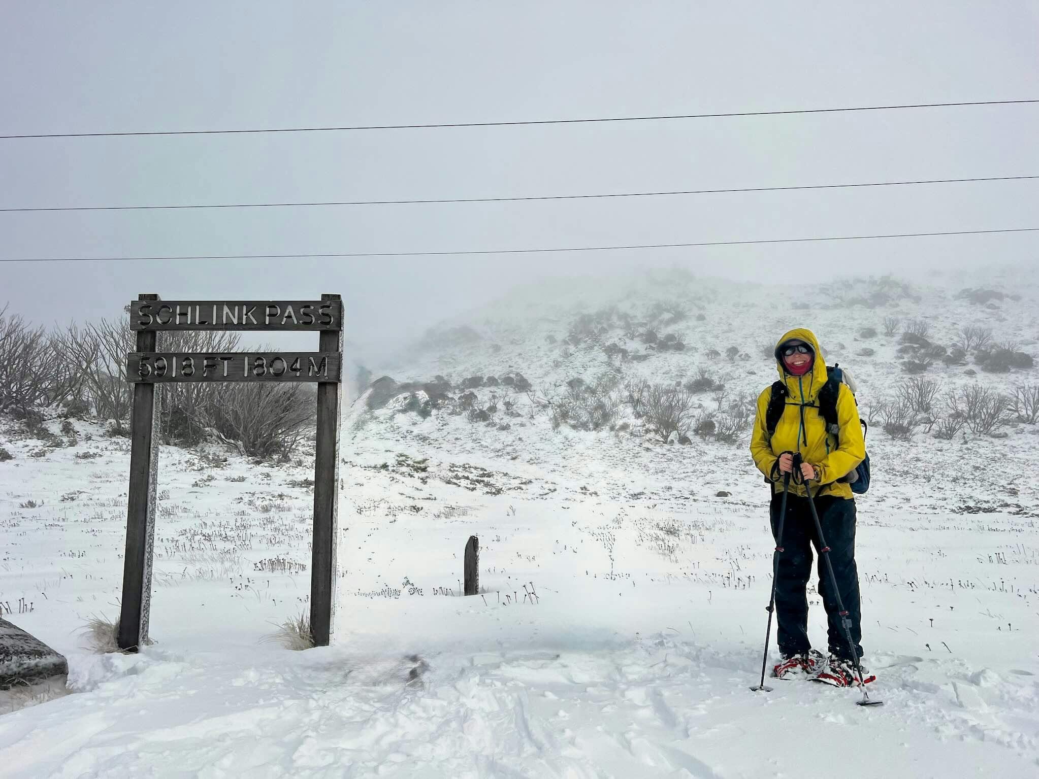 Ein Wanderer auf Schneeschuhen in einer gelben Jacke auf schneebedeckten Bergen