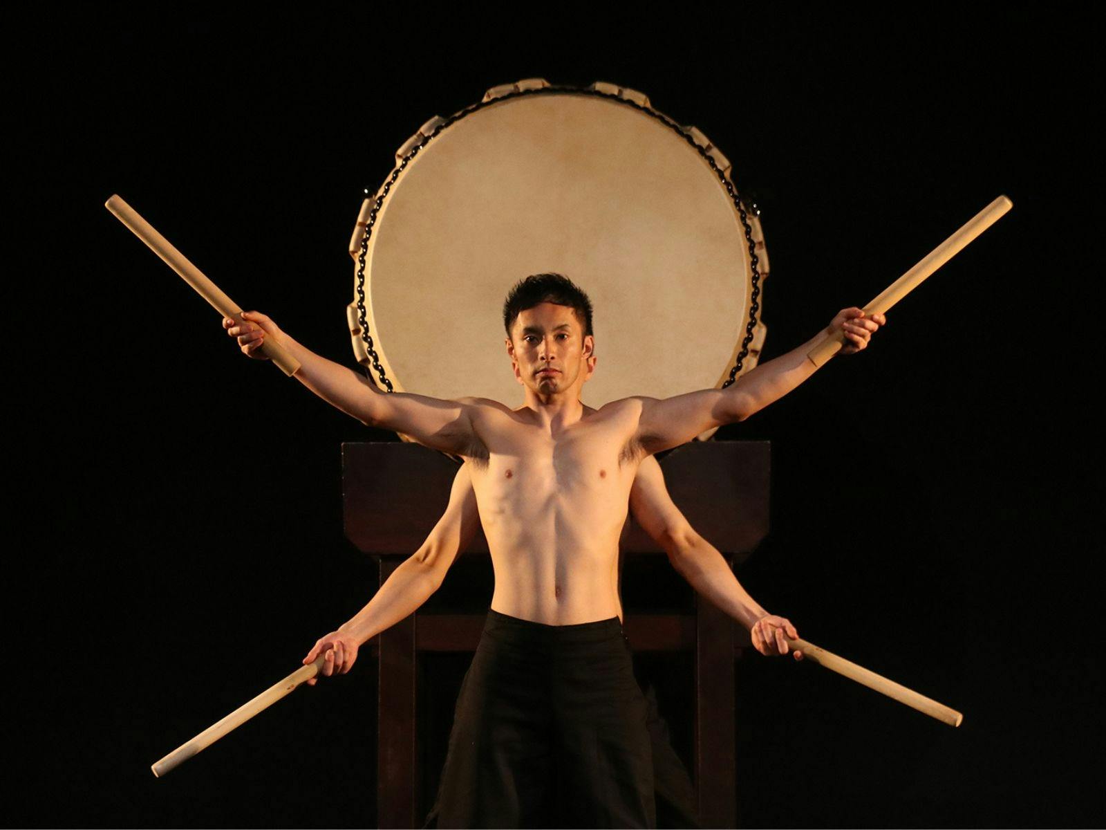 two performers on stage with a large drum behind them