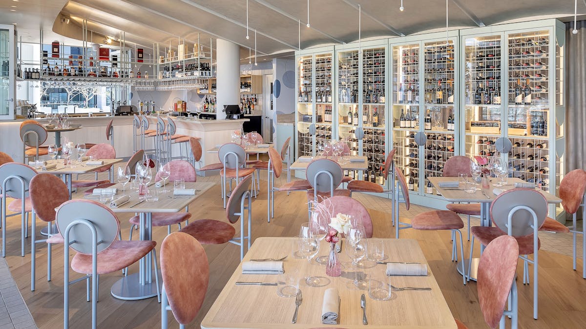 Aloria's inside dining room, with pink chairs and a wine cellar wall