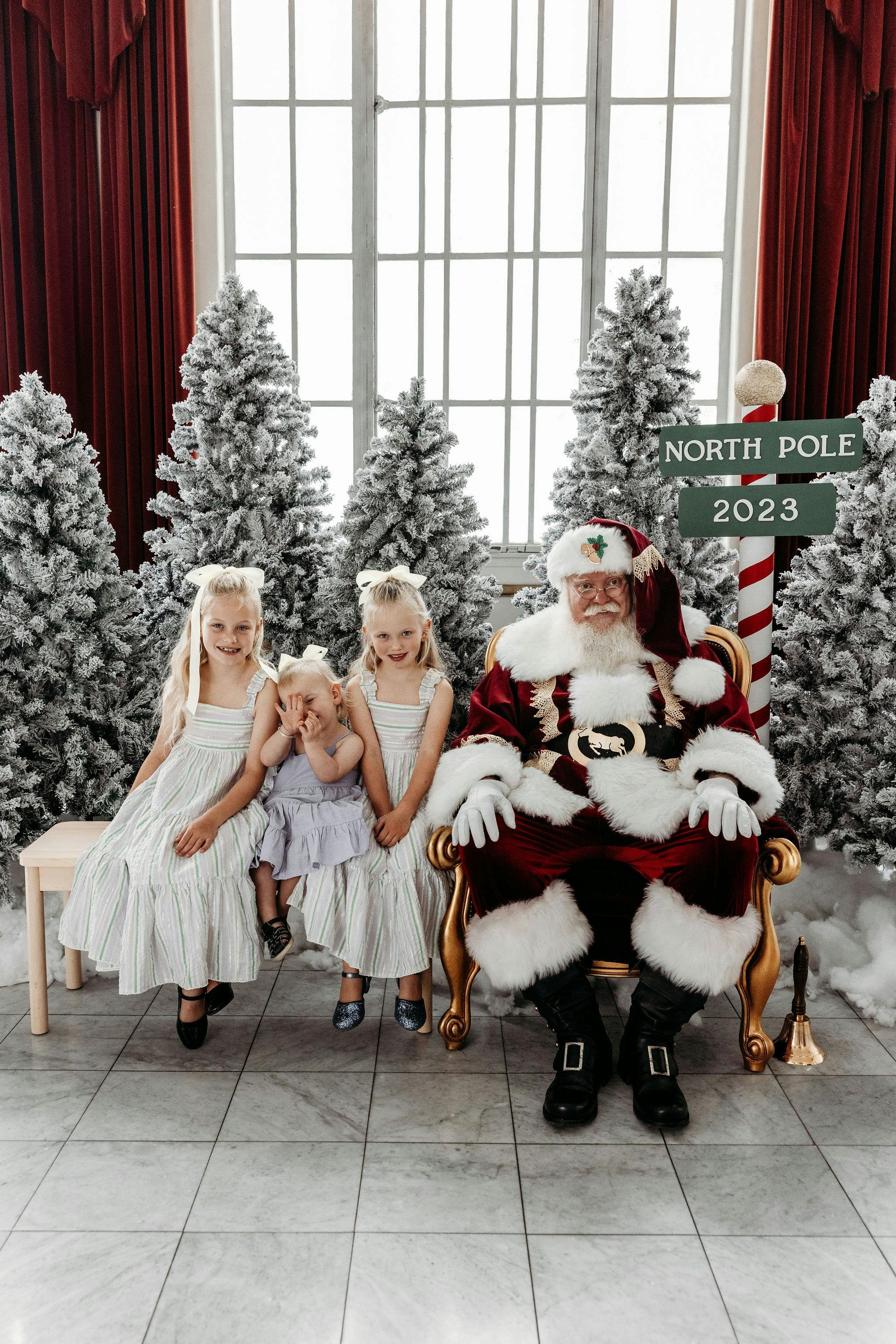 Santa with a child sitting on his lap. A family sitting with santa.