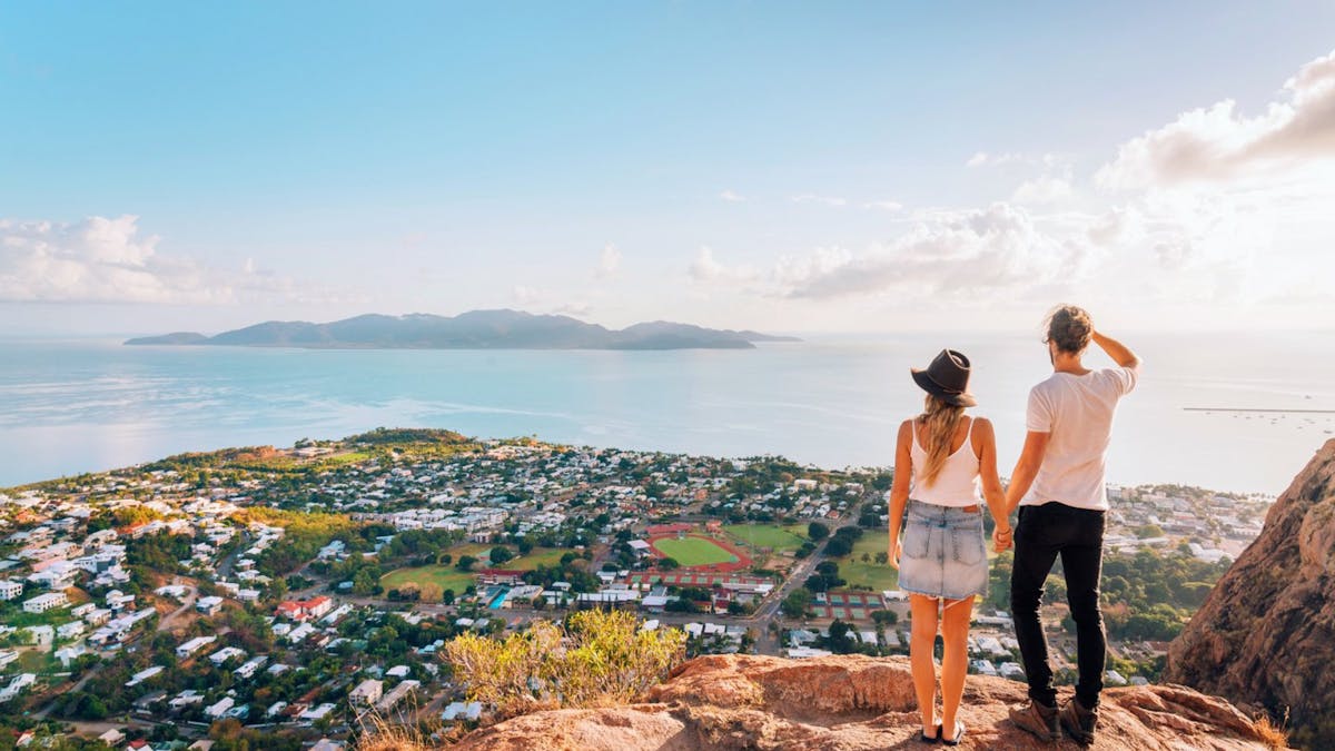 Two people standing on a hill looking over a body of water