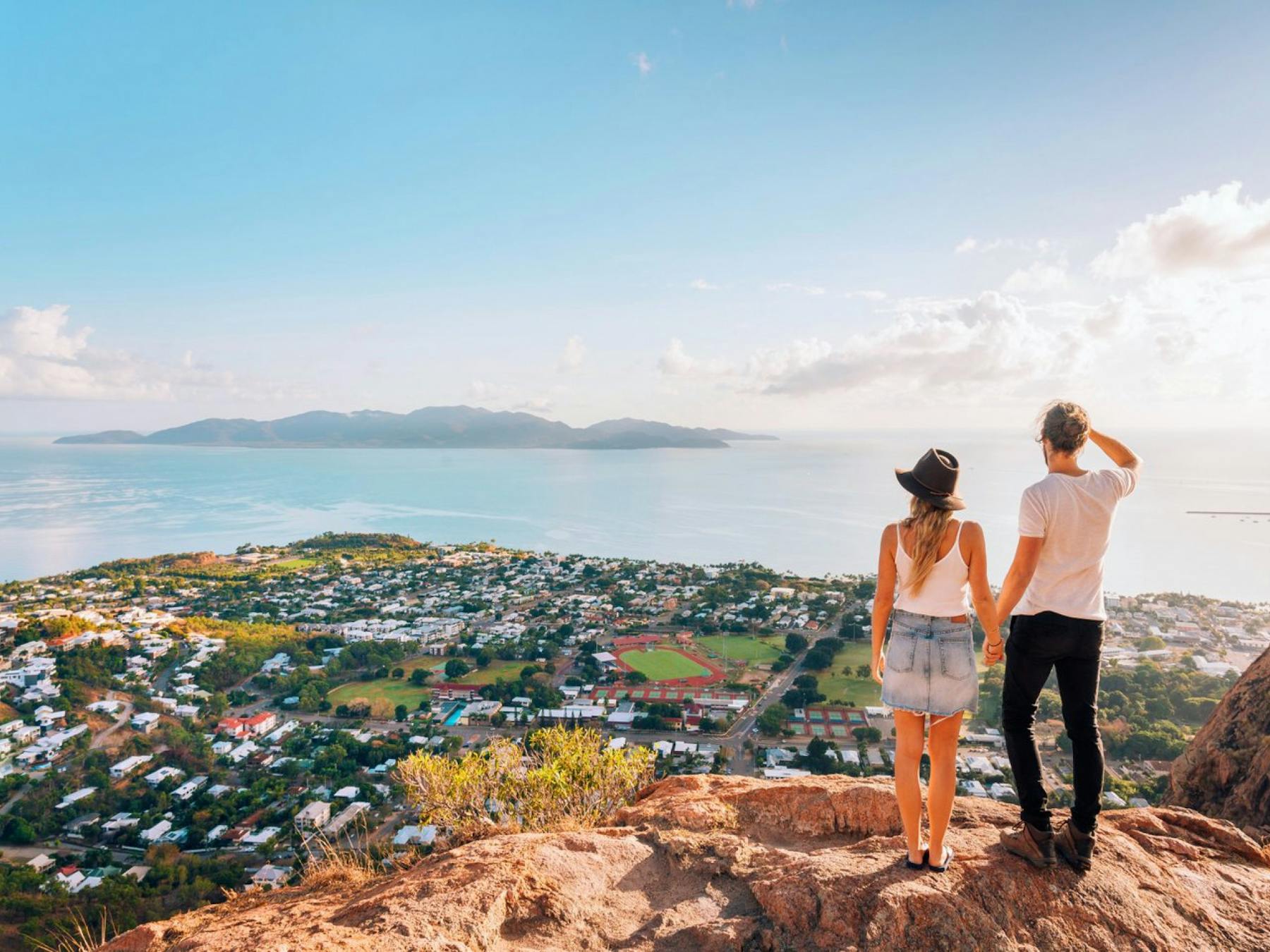 Two people standing on a hill looking over a body of water