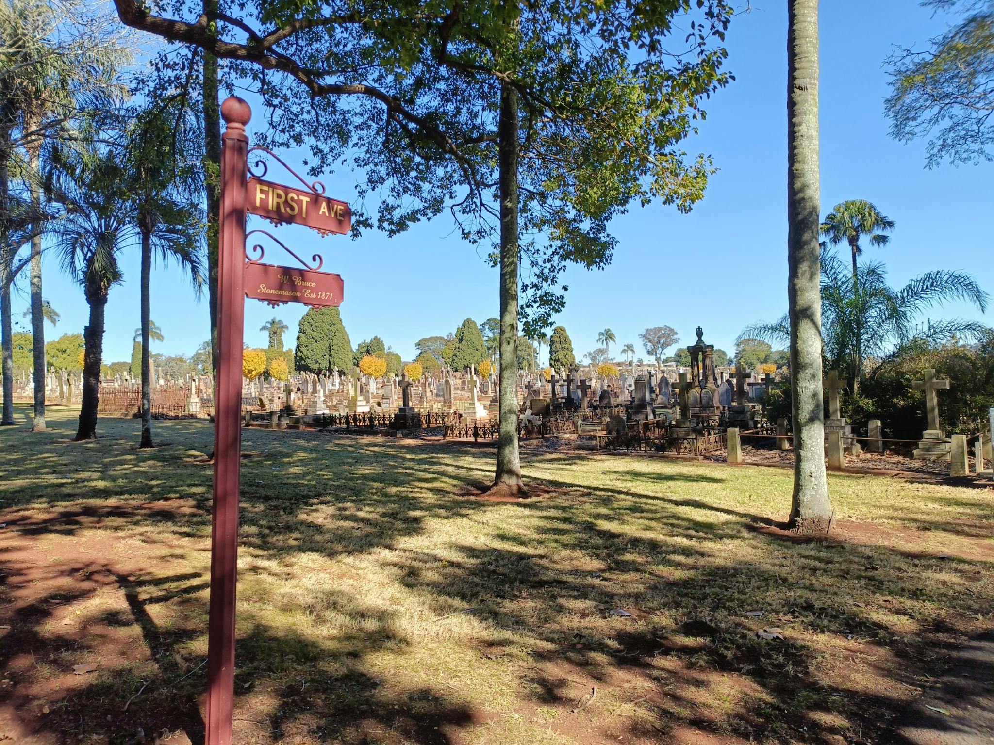A decorative road sign that says 'First Ave', graves in the background