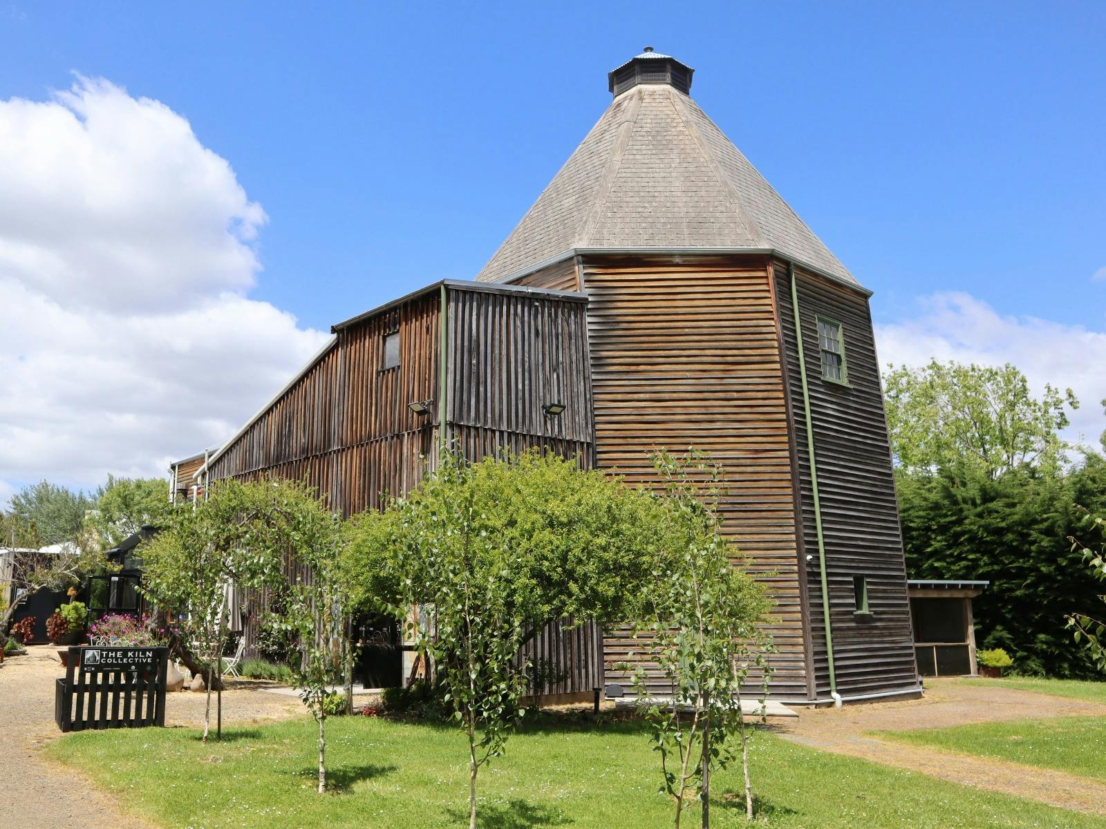 Historic timer hop kiln building surrounded by lawn.