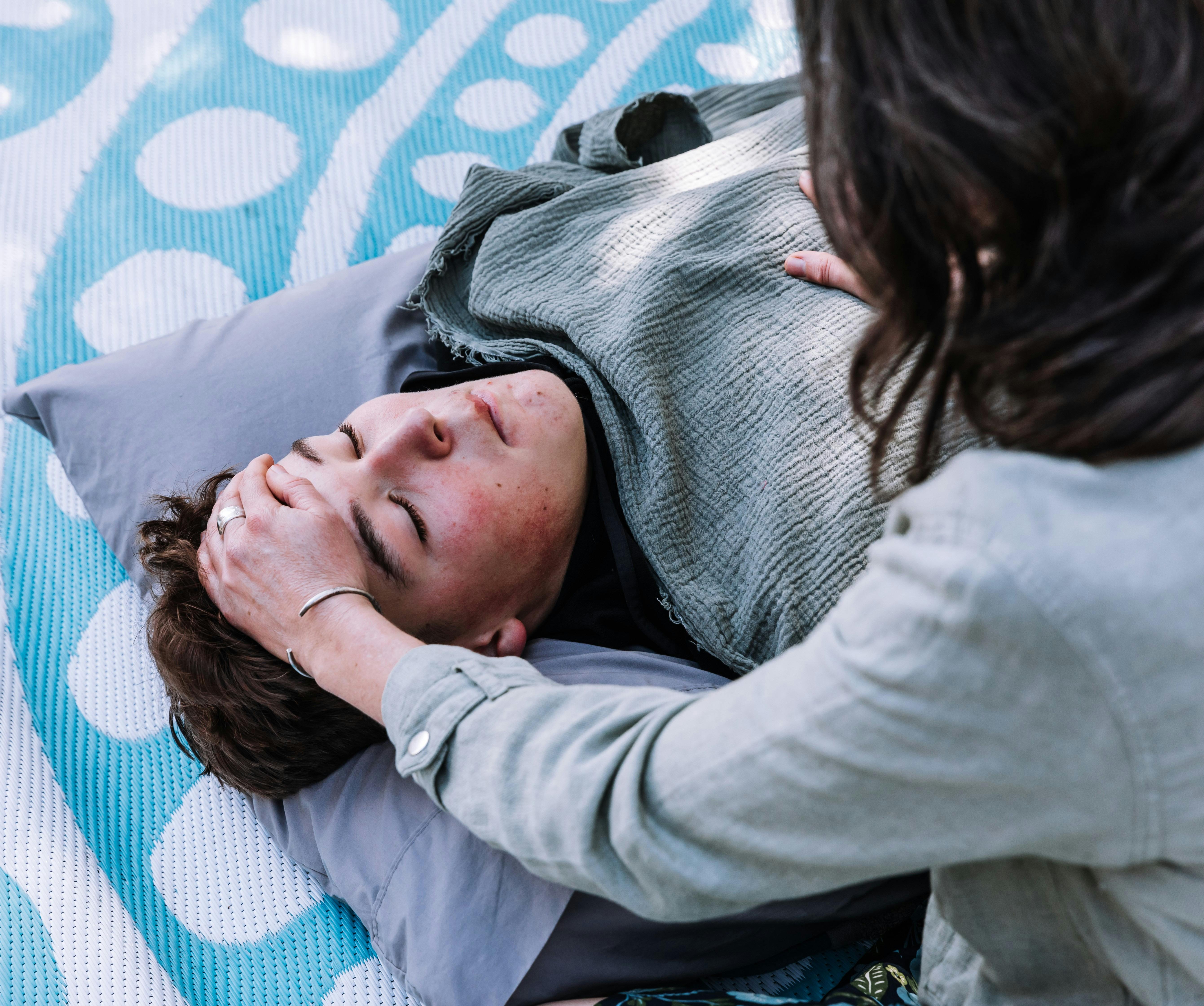 Person receiving Shamanic Healing outdoors, with practitioner gently supporting their head.